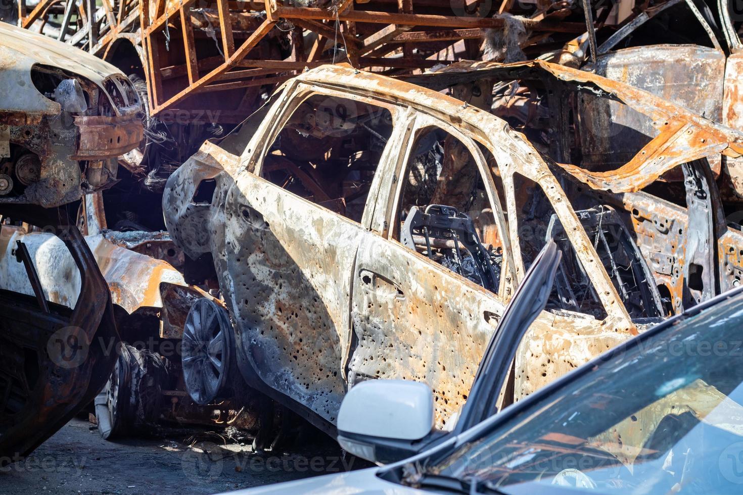 The car burned down completely, even the tires burned out. Burnt out car crash after fire. The bomb shell of the terrorist attack blew up civilians. Disaster zone. Abandoned car on the road. photo
