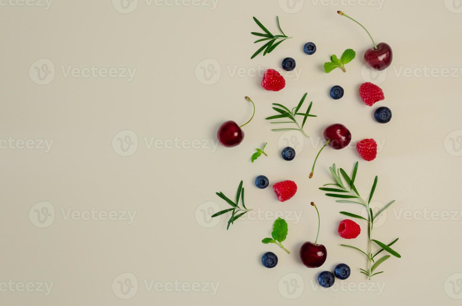 Fresh cherry, blueberry, raspberry, mint and rosemary leaf on top view with beige color background for healthy food concept. photo