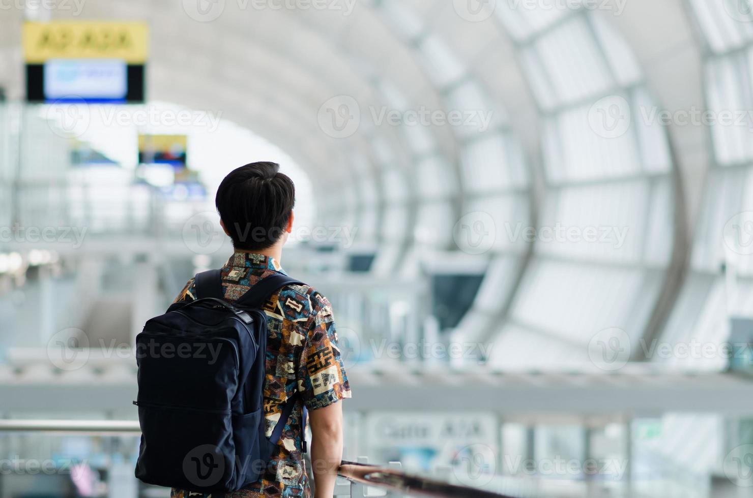 Asian man with carry bag standing and looking forward waiting to travel after pandemic. photo