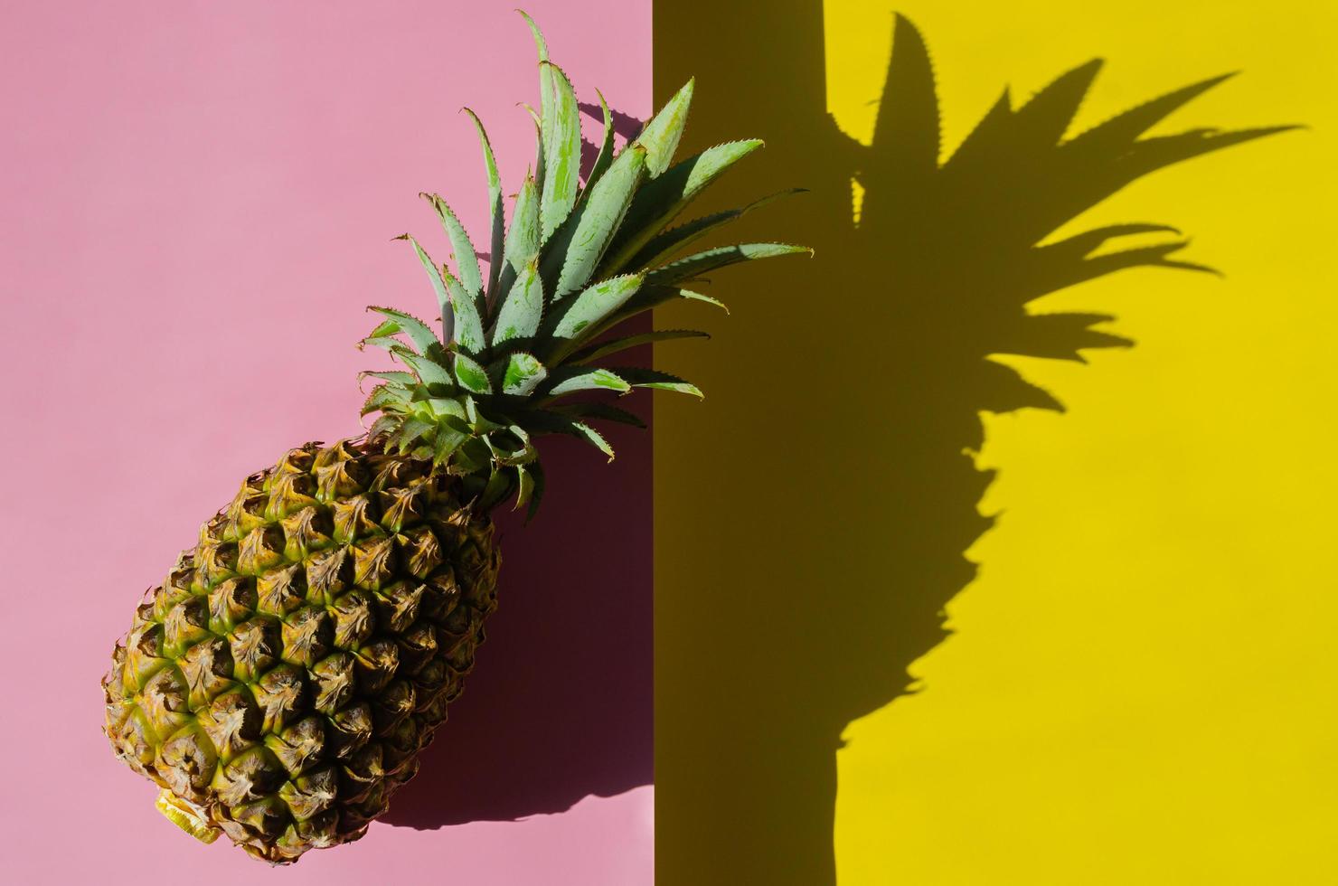 Pineapple on pink background with its shadow photo