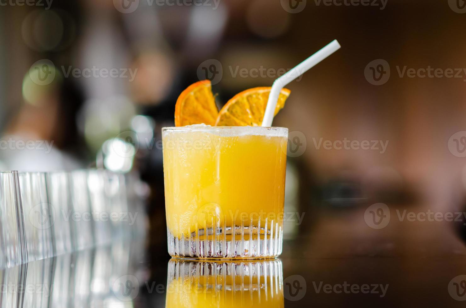 A glass of orange cocktail puts on table of the bar for Holiday and summer drink concept. photo