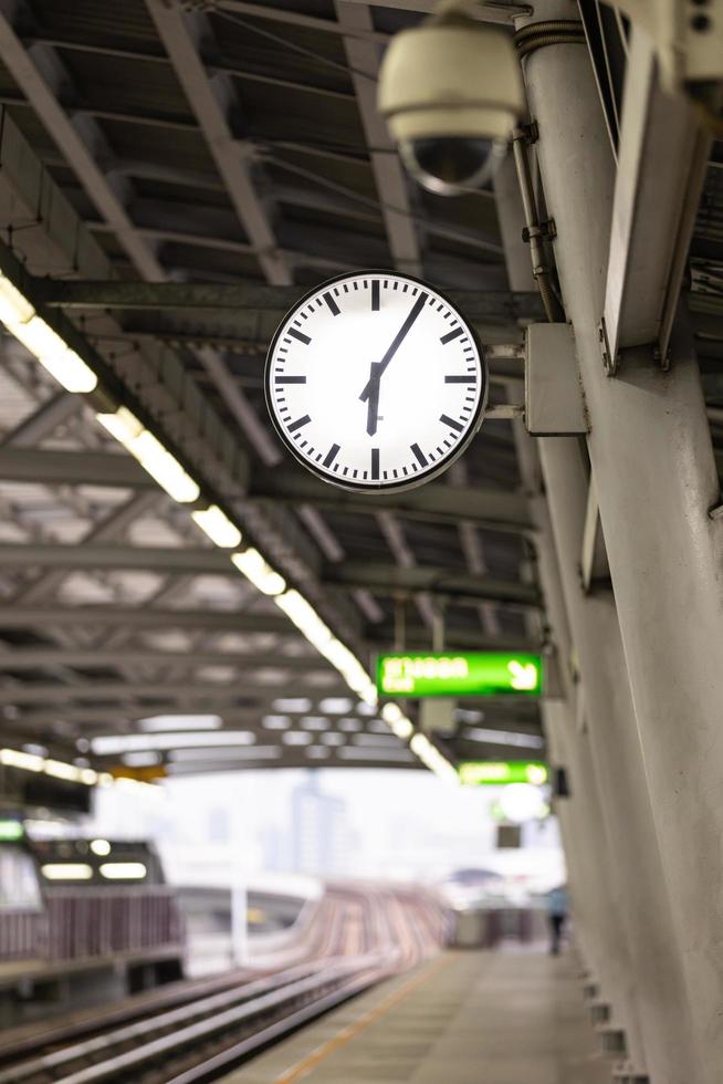 gran reloj blanco público en la estación de tren vacía con fondo borroso. foto