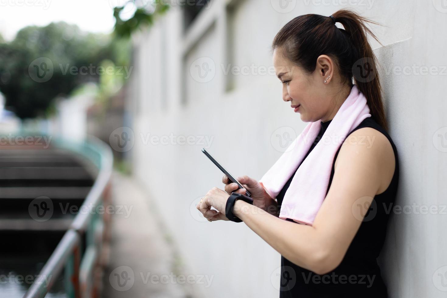 Adult mature women in sportswear compare, sync or reading results of fitness application on screen of smartphone and smartwatch devices after workout or exercise. Concept of good health care photo