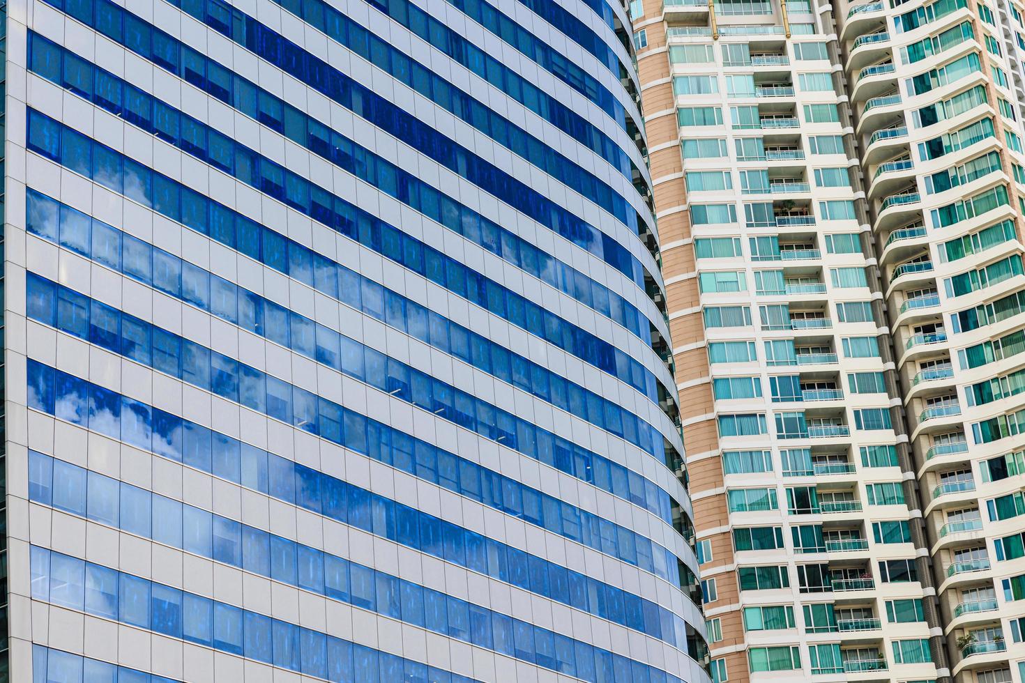 Blue sky and clouds reflected on the glass of office business buildings in the city center on a bright sunny day. photo