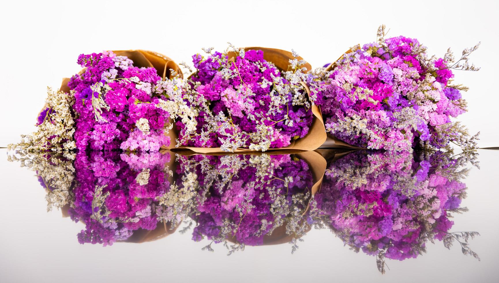 Close up shot of violet and colorful small flowers arranged in three bouquets. Fresh purple flowers bunch with reflection on floor photo