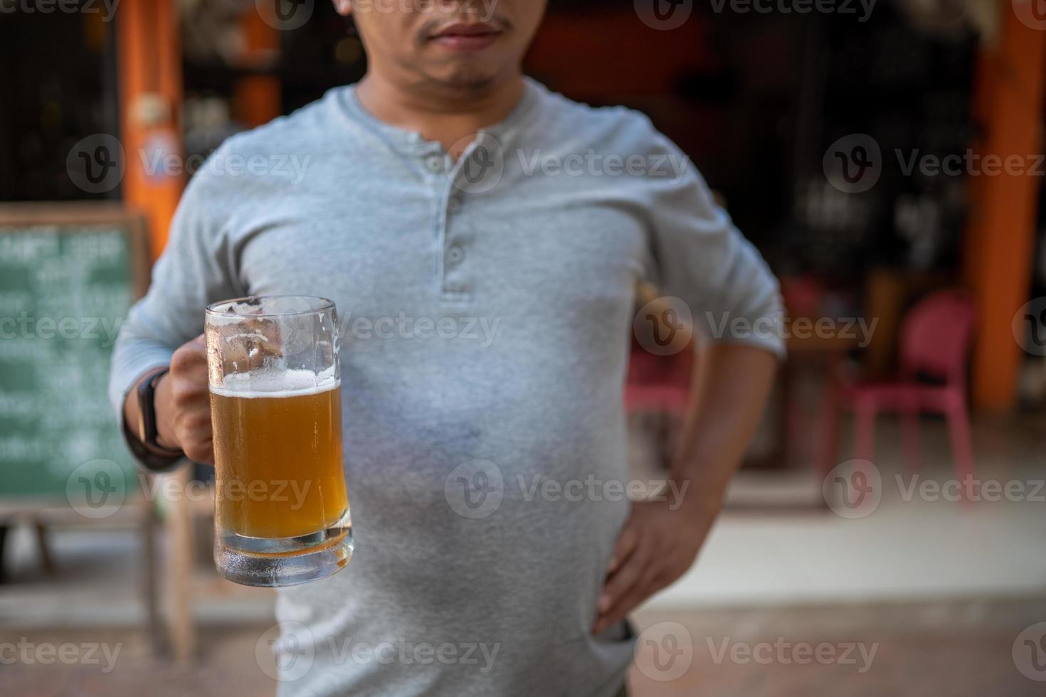 Young man holding a glass of beer and is it true that drinking beer makes you fat photo