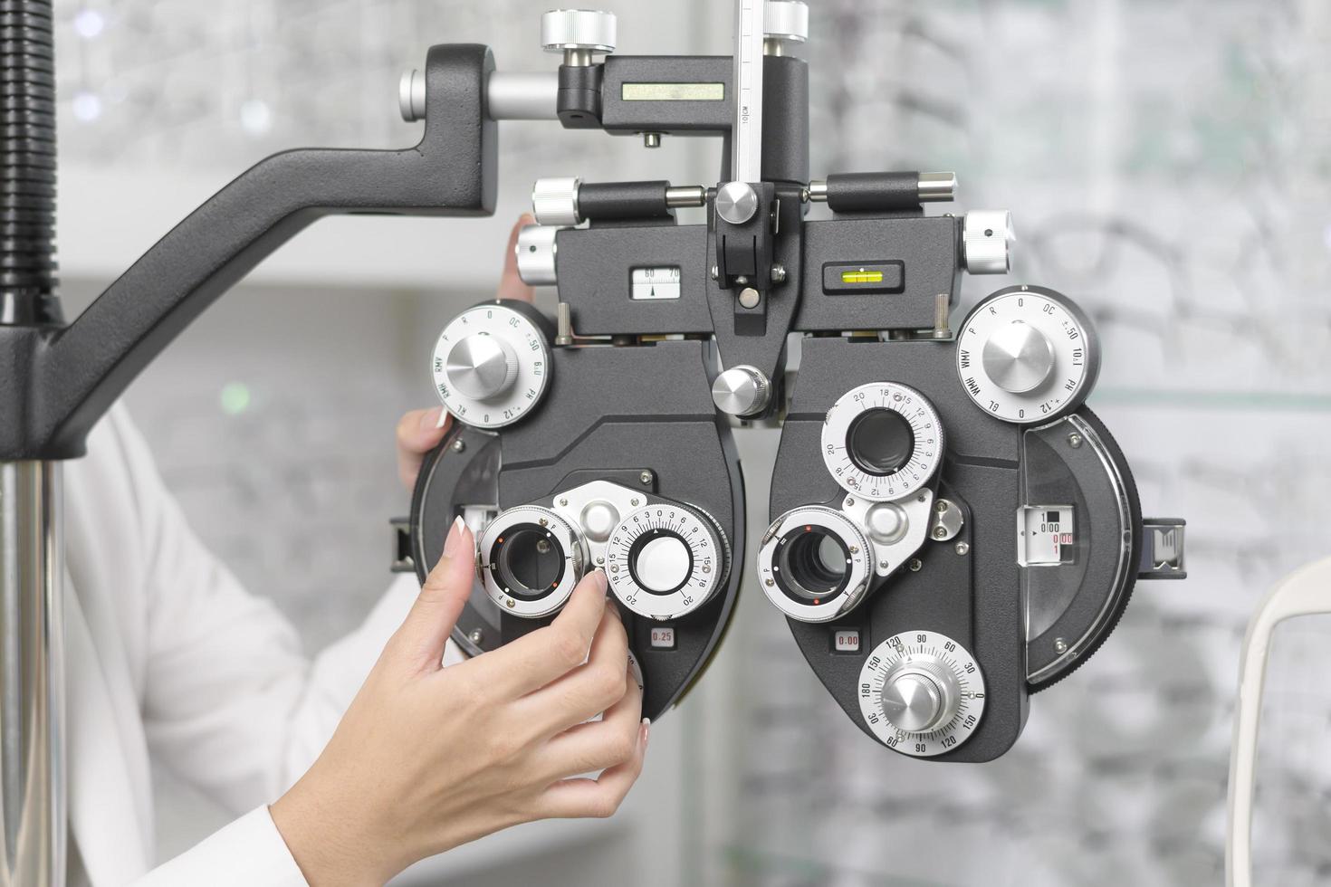 Young ophthalmologist doing visual test for customer using Bifocal Optometry eyesight measurement device in optical center, eyecare concept. photo