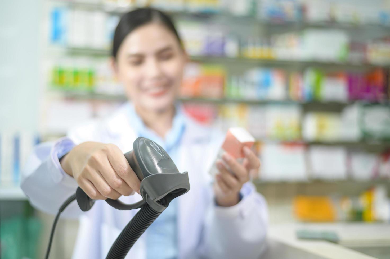 Farmacéutica femenina escaneando código de barras en una caja de medicamentos en una farmacia moderna. foto