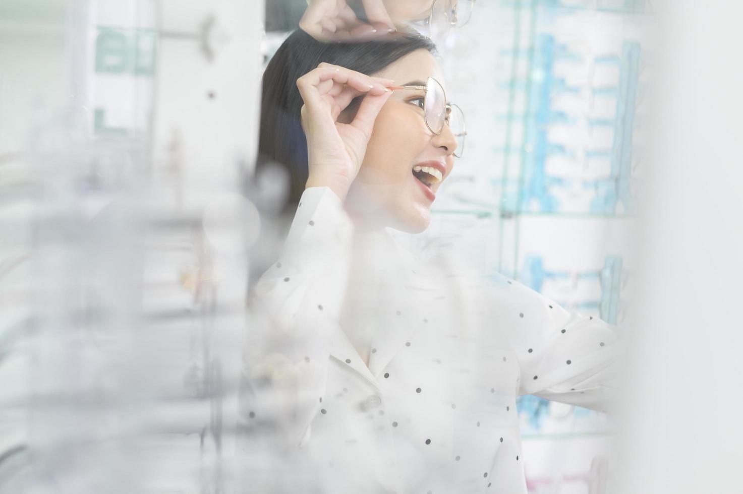 Young female customer trying on glasses and taking a selfie in optical center, Eyecare concept. photo