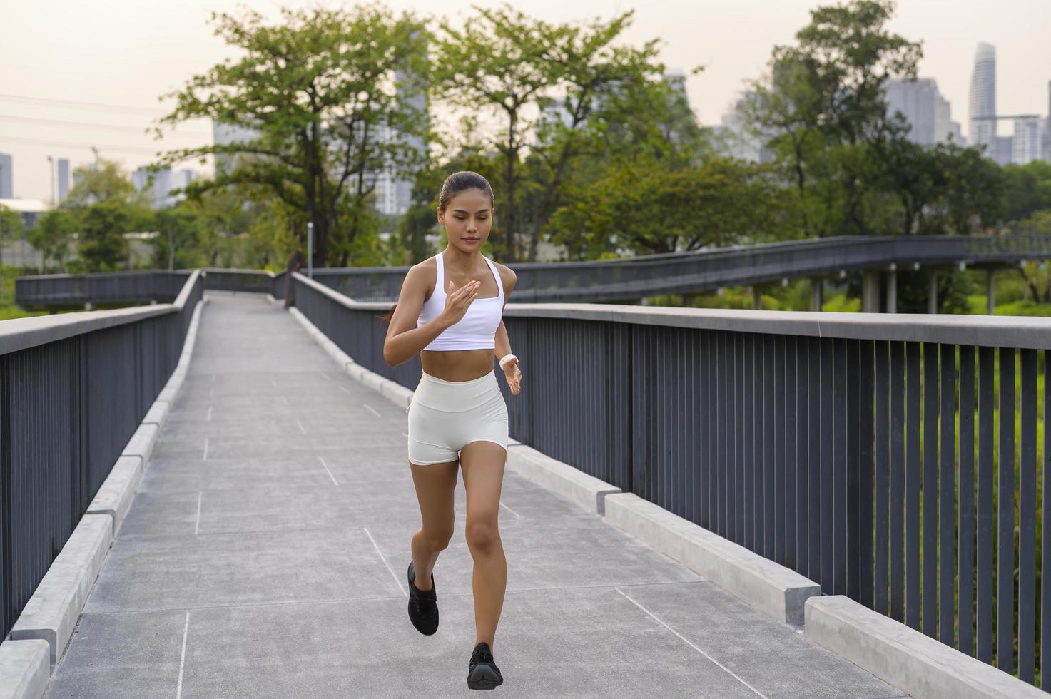 mujer joven fitness en ropa deportiva trotando en el parque de la ciudad, saludable y estilos de vida. foto