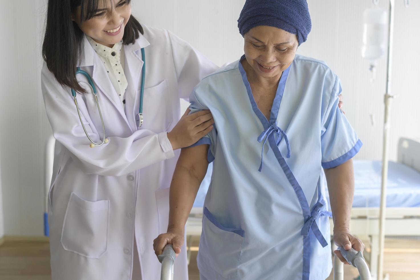 médico que ayuda a una paciente con cáncer que usa pañuelo en la cabeza con un andador en el hospital, atención médica y concepto médico foto