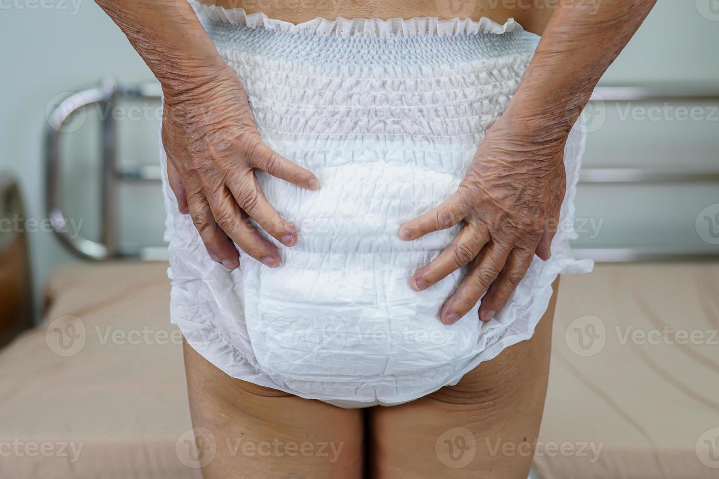 Asian elder senior woman patient wearing adult incontinence diaper pad in hospital. photo
