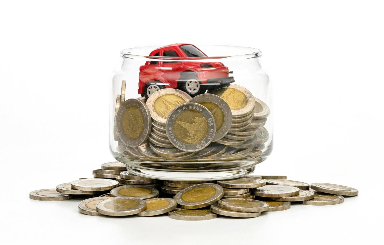 coins in glass bottle and red car on white background,business saving and investment concept photo