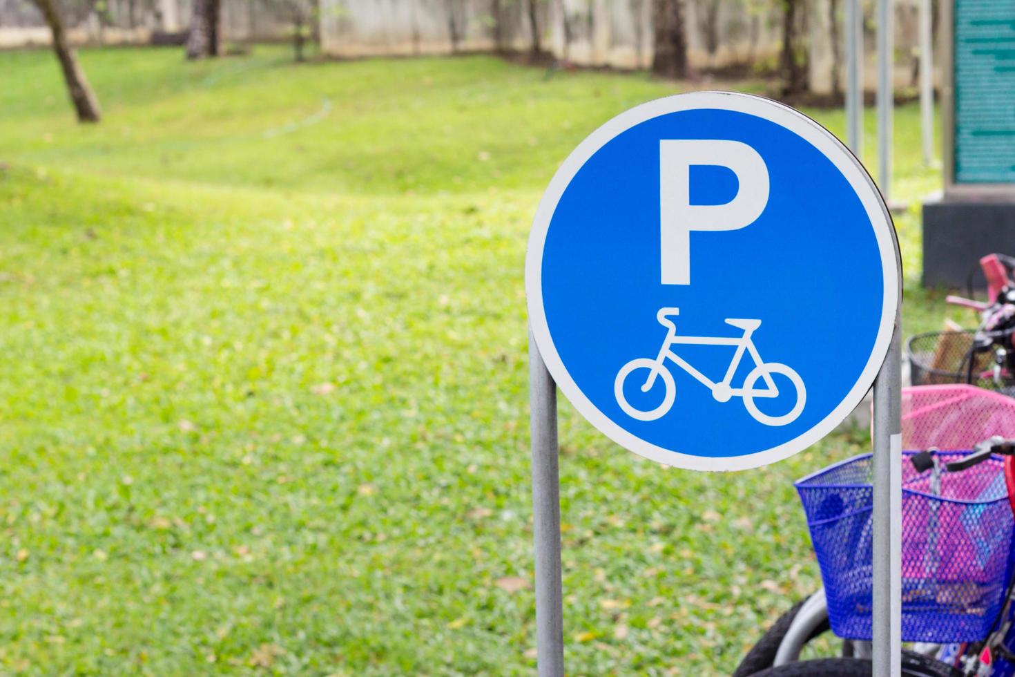 Bicycle parking sign in public park against grass background photo