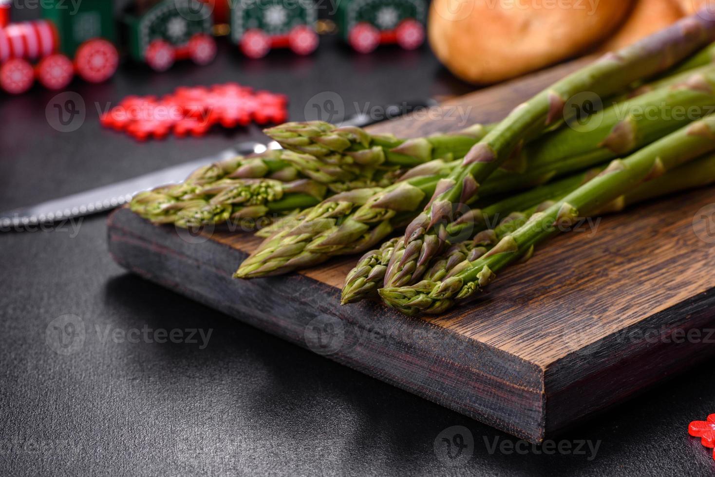 Delicious fresh raw green asparagus stalks on wooden cutting board photo