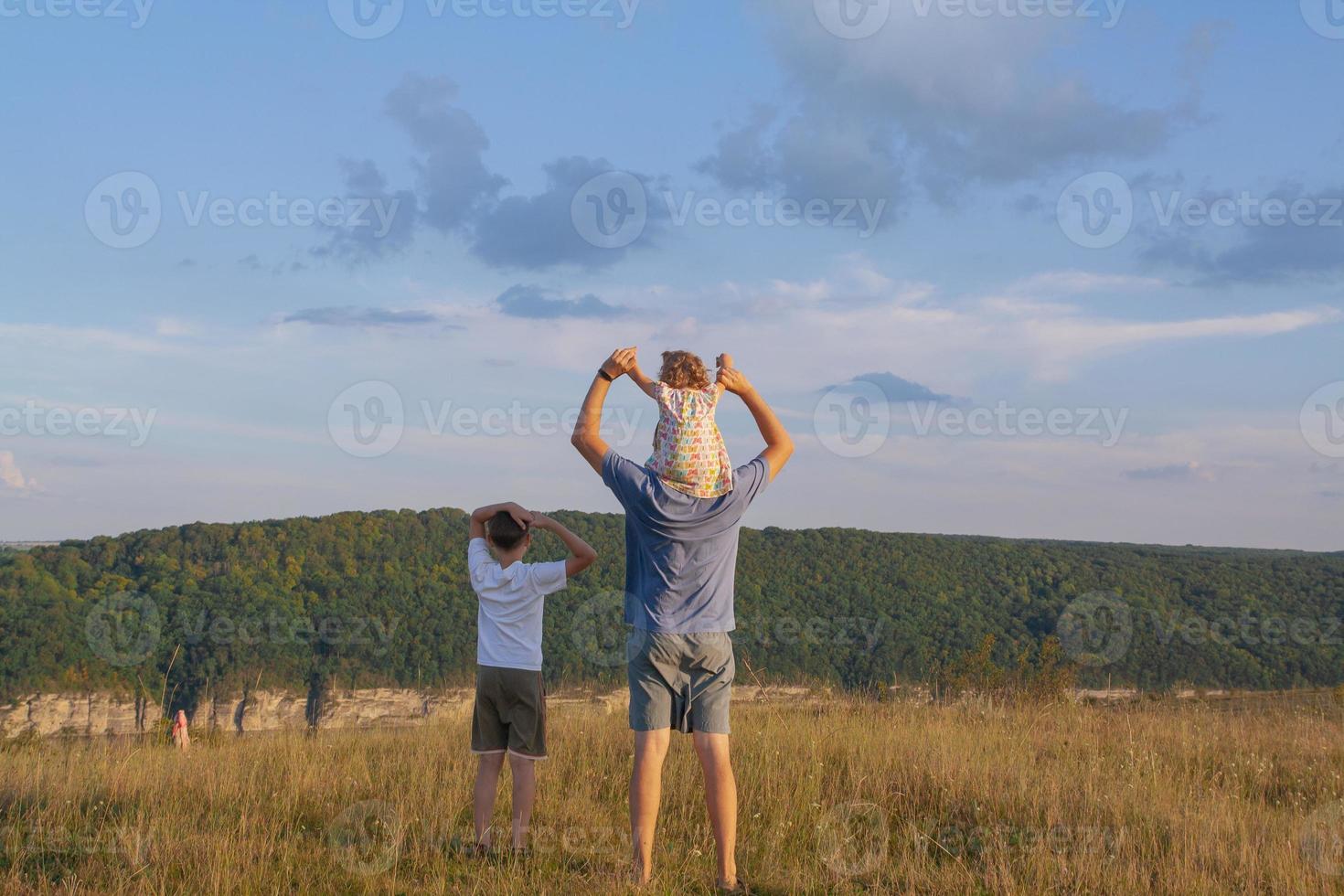 Father with two children on shoulders outdoors. Family in nature in the village concept photo