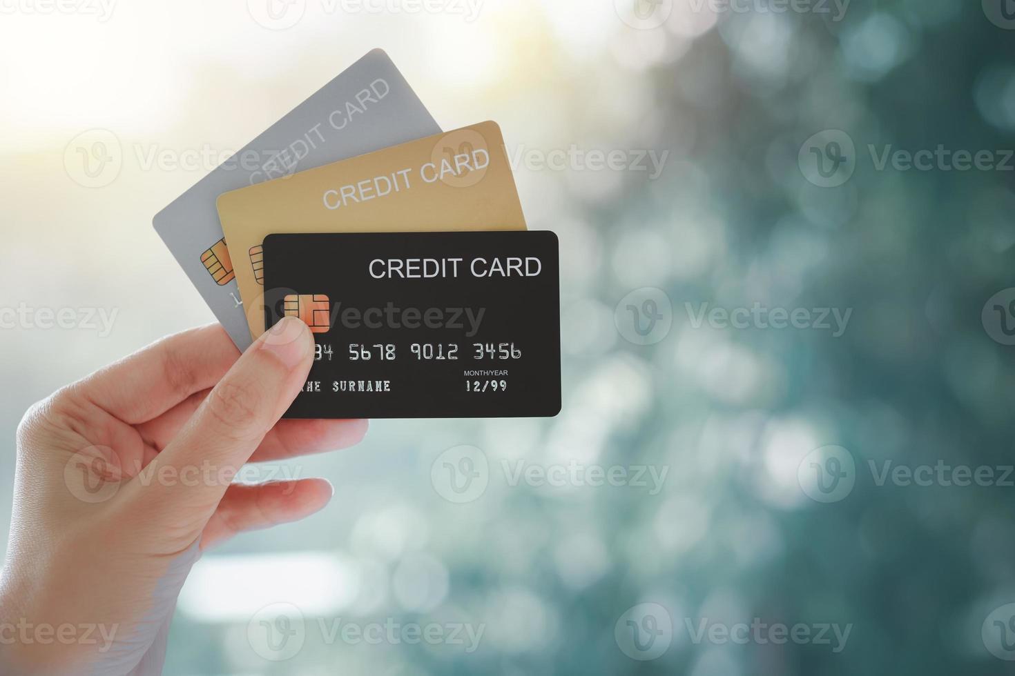 mano de mujer sosteniendo varias tarjetas de crédito sobre fondo natural bokeh. foto