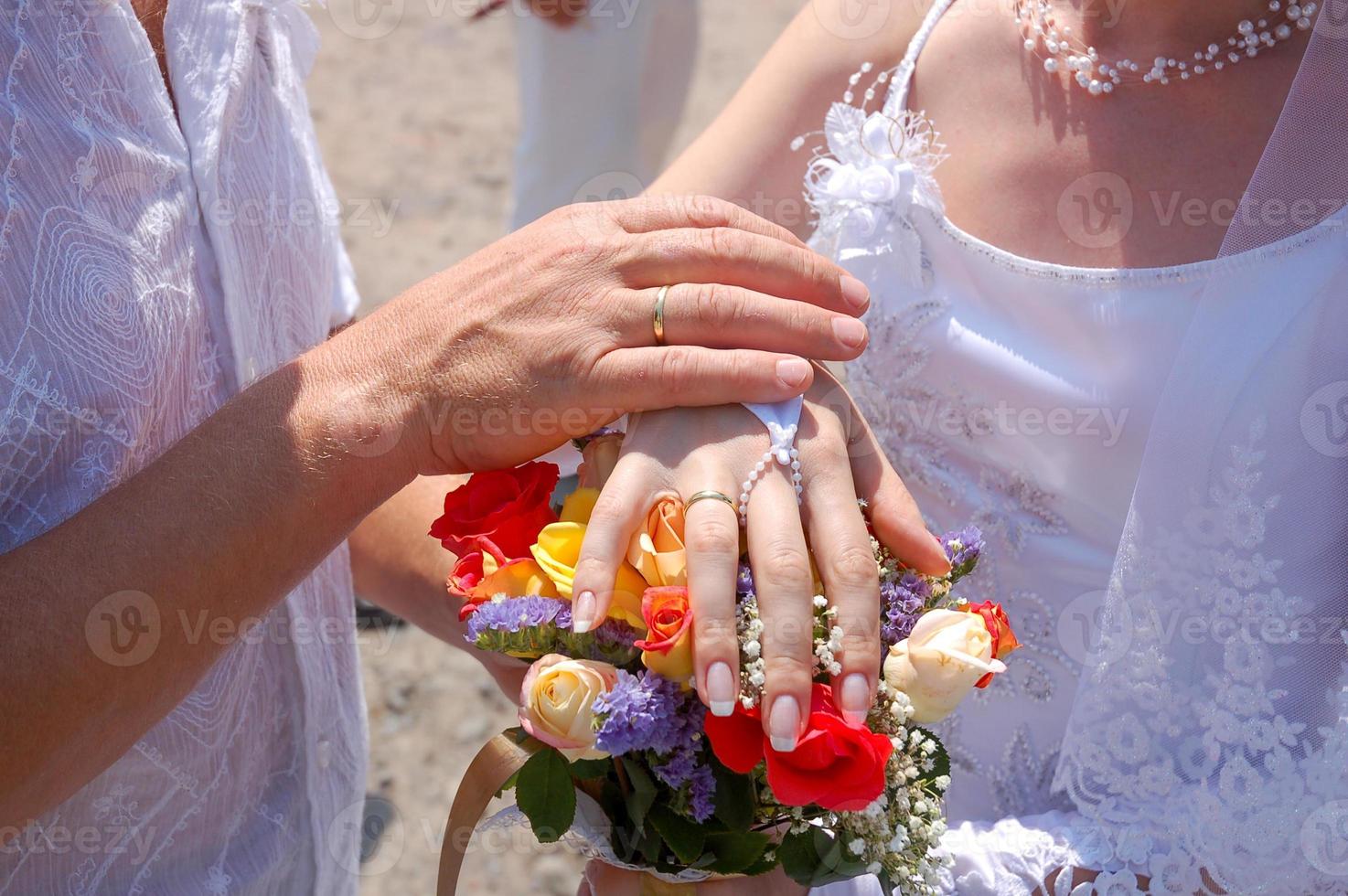 Hands of the bride and groom above a bouquet of flowers photo