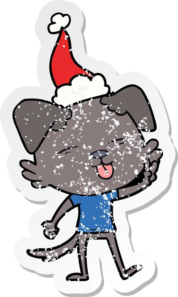 distressed sticker cartoon of a dog sticking out tongue wearing santa hat vector