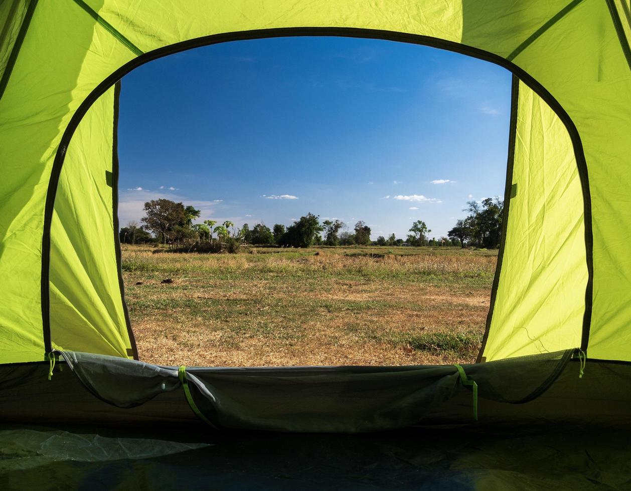 viajero carpa verde camping viajes al aire libre. vista desde el interior de la carpa ver mirador una alta montaña desde la distancia en el paisaje de verano. durante el día de la tarde adecuado para dormir y descansar el cuerpo foto