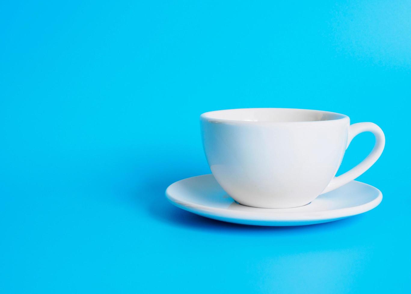 White coffee cup top view photograph On a white saucer The inside of the glass ceramic looks empty. Waiting for hot coffee to be refilled to drink to feel refreshed and alert on a blue background. photo