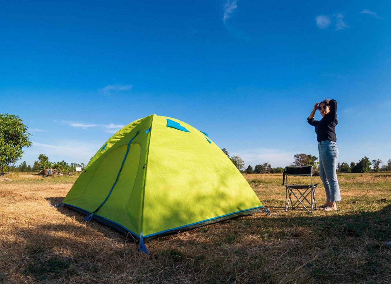 Asian female tourists are sitting happy free with green tent for traveler sits on  wide field, overlooking evening time Of Private area Thailand for camping getaway During long holiday for travel. photo