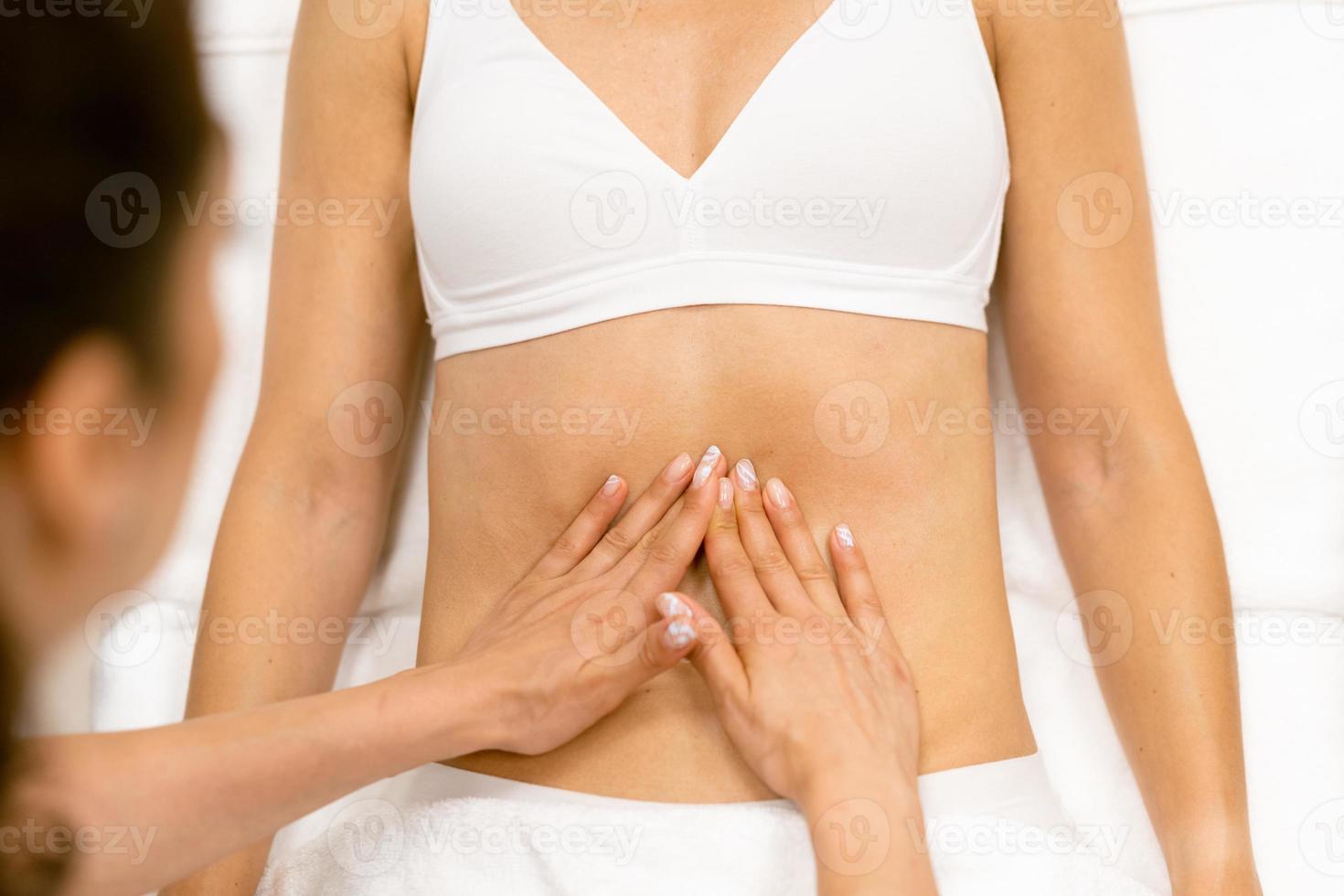 Middle-aged woman having a belly massage in a beauty salon. photo