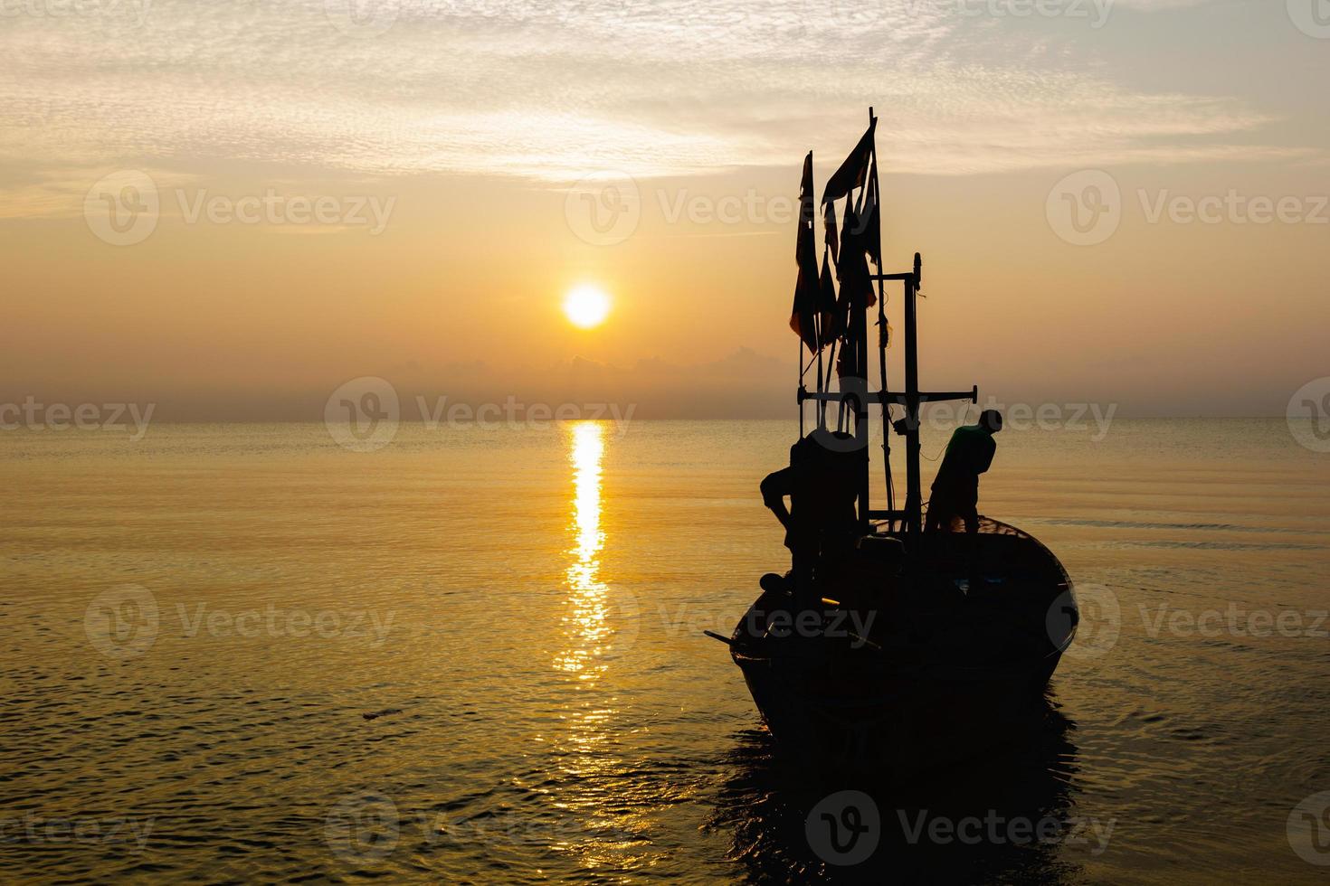 Silhouette of two people on a fishing boat that is about to go fishing in the morning sun.copy space. photo