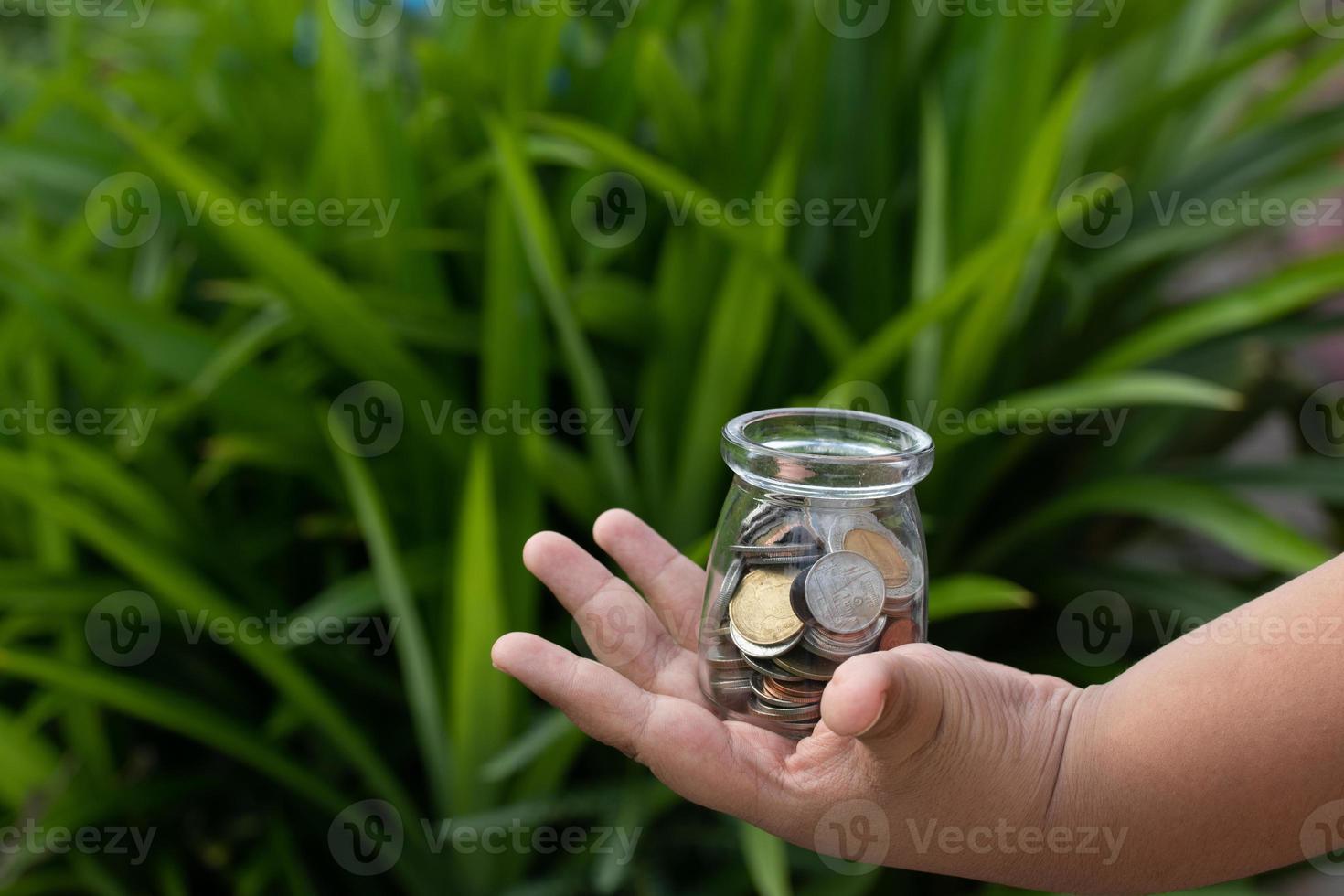 Coins in a bottle in a glass hand, concept of saving money, copy space photo