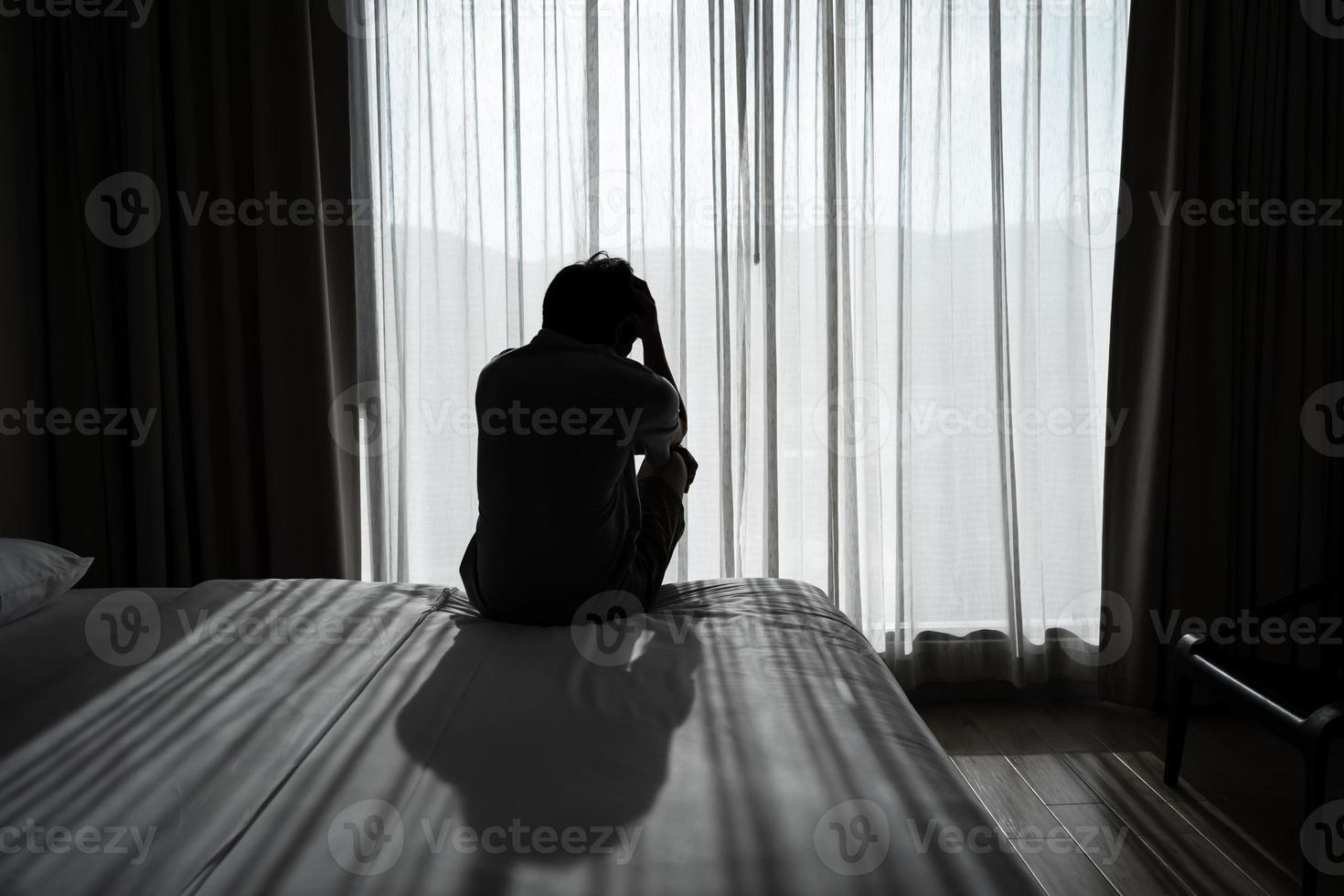 Lonely young man feeling depressed and stressed sitting in the dark bedroom, Negative emotion and mental health concept photo