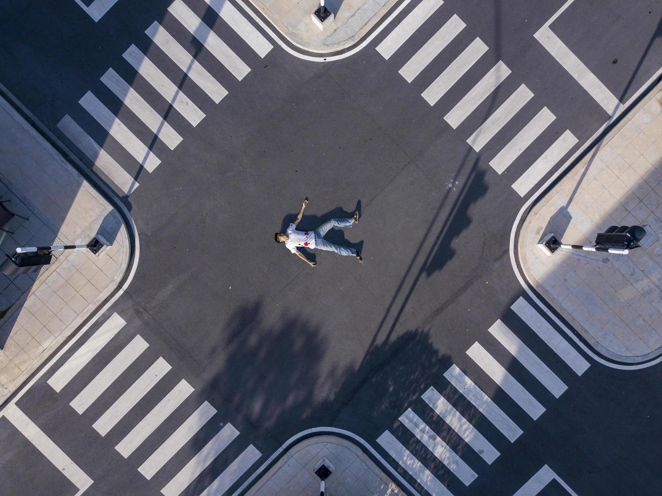 Seriously injured pedestrian man laying down on the middle of crossroad intersection street after car crash with blood for safety traffic road and transportation photo