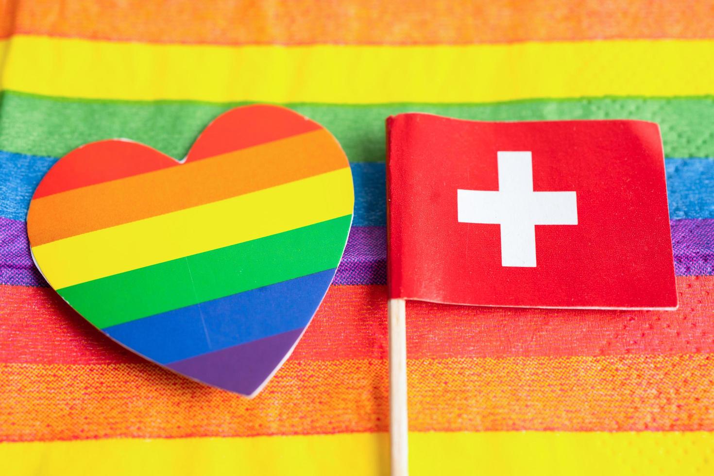 bandera de suiza en el fondo del arco iris símbolo del movimiento social del mes del orgullo gay lgbt la bandera del arco iris es un símbolo de lesbianas, gays, bisexuales, transgénero, derechos humanos, tolerancia y paz. foto