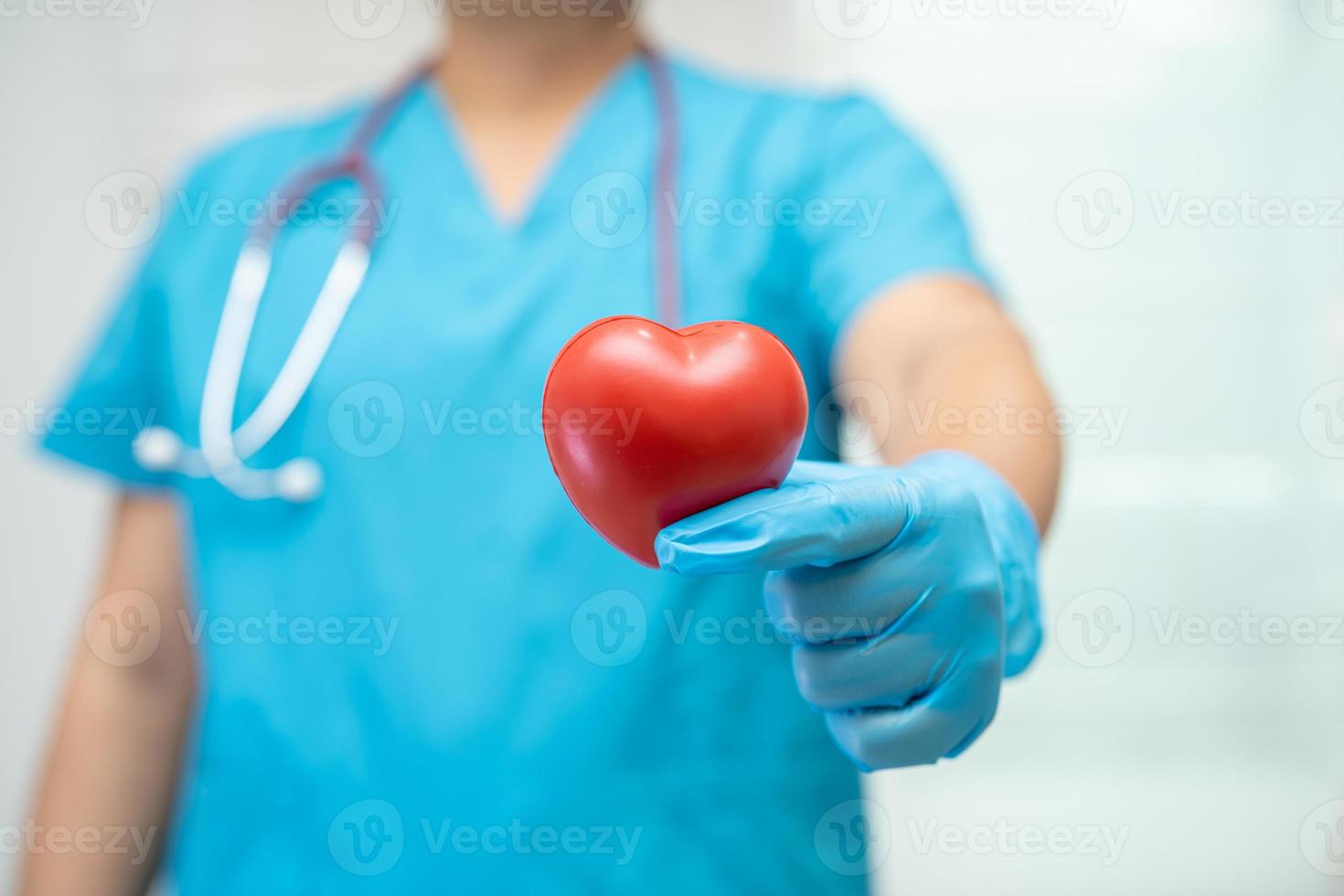 Doctor holding a red heart in hospital ward, healthy strong medical concept. photo