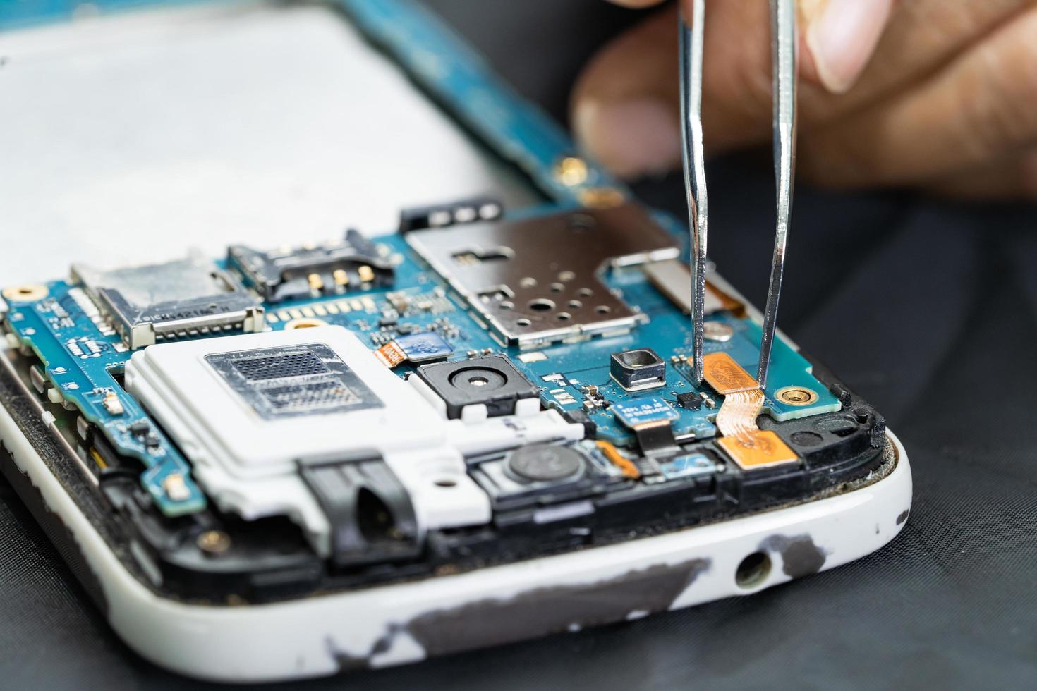 Technician repairing inside of mobile phone by soldering iron. Integrated Circuit. the concept of data, hardware, technology. photo