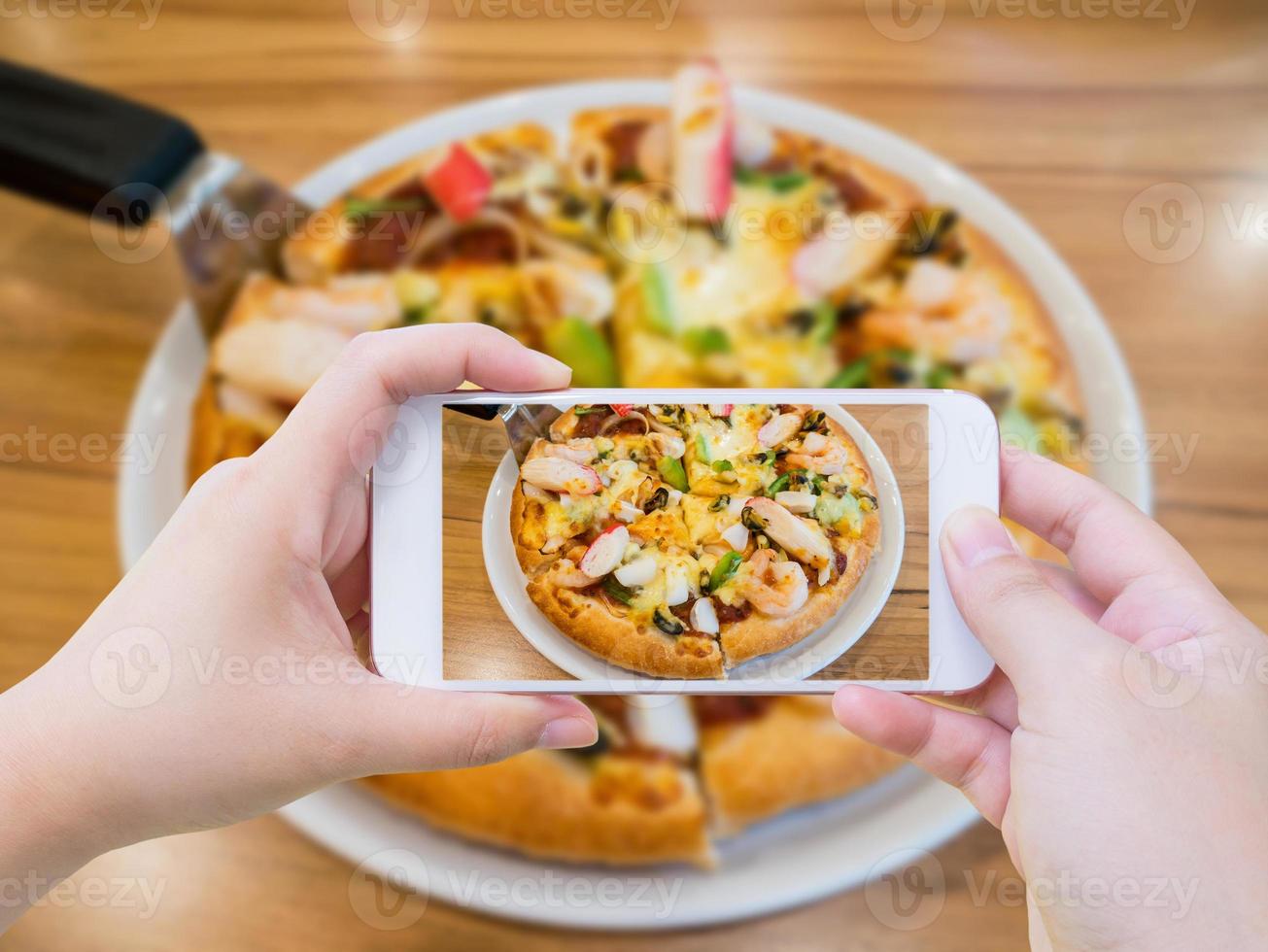 mujer tomando fotos de pizza con teléfono inteligente móvil