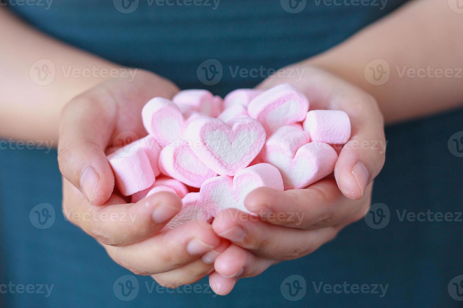 mano de mujer sostenga malvaviscos en forma de corazón para el día de san valentín foto