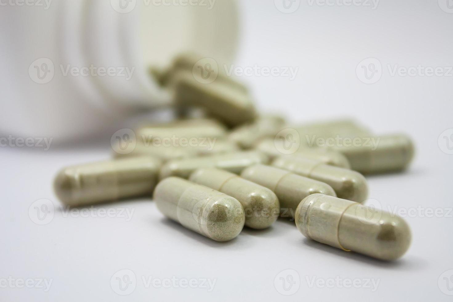 herbal capsules spilling out of a bottle photo