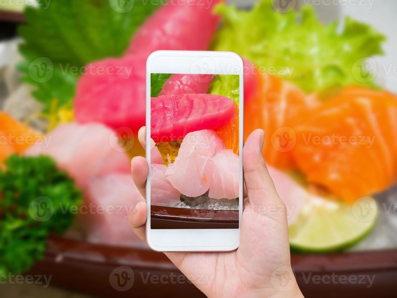 Female hand taking photo of sashimi sushi set