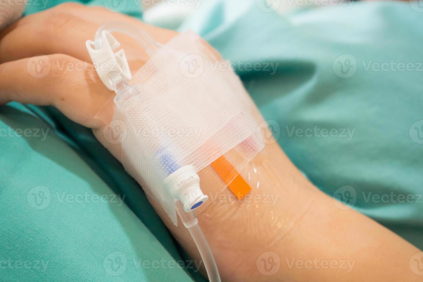 Asian woman patient hand on IV drip with saline solution, fluid replacement therapy photo