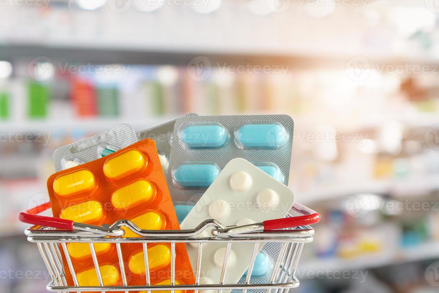 tableta de píldora de medicina en la cesta de la compra con estantes de farmacia fondo borroso foto