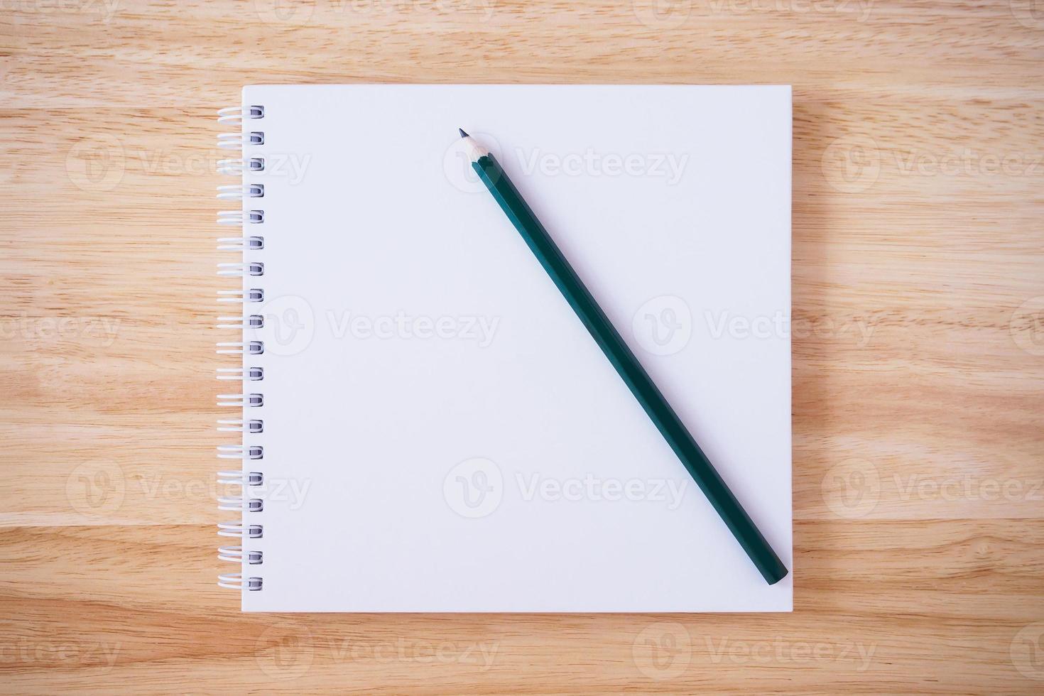 vista superior del cuaderno de tapa blanca con lápiz en el escritorio de madera marrón foto
