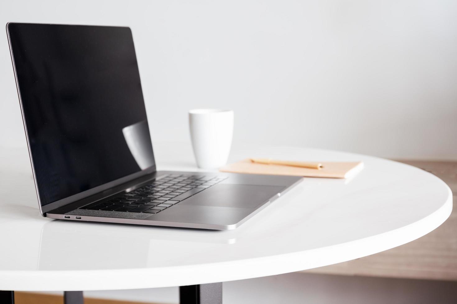 simule una computadora portátil con pantalla en blanco y una taza de café con otros suministros de oficina. foto