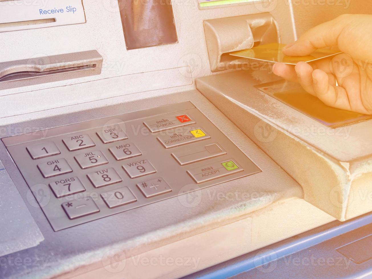 female hand inserting ATM card into ATM bank machine photo