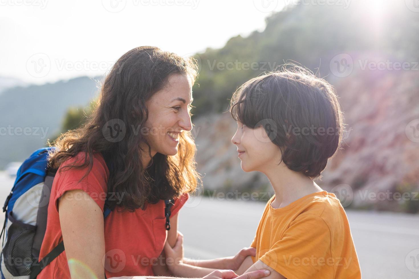 A boy hugs his mother, a woman spends time with a child in nature photo