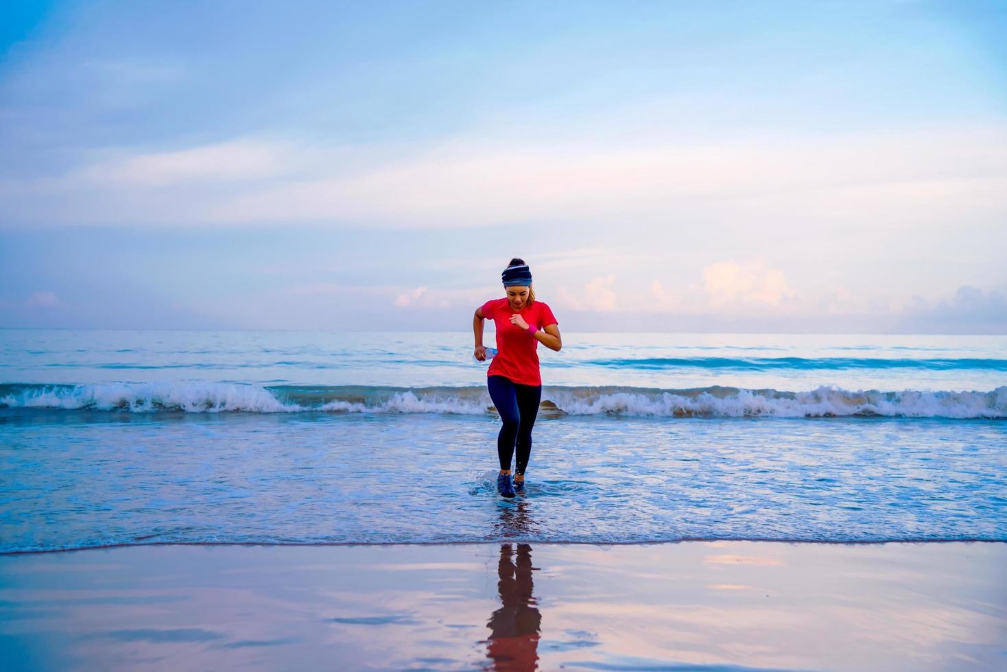 Girl running workout jogging on the beach in the morning. relax and happy with running on the sea. in summer photo