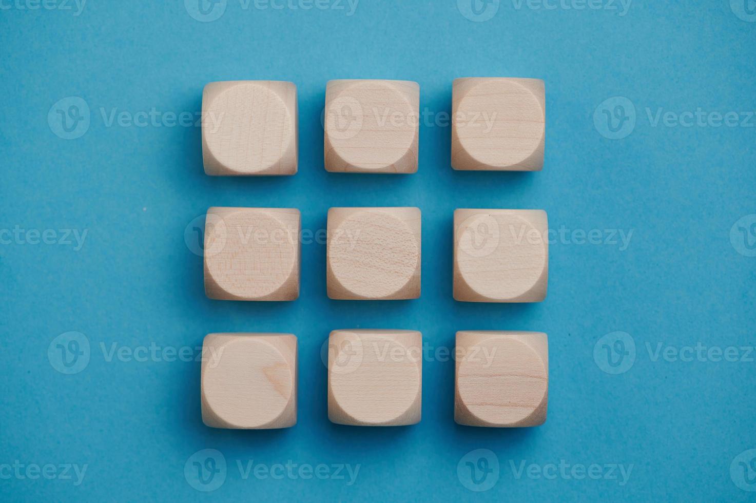 nine wooden cubes on blue background in three rows, copy space photo