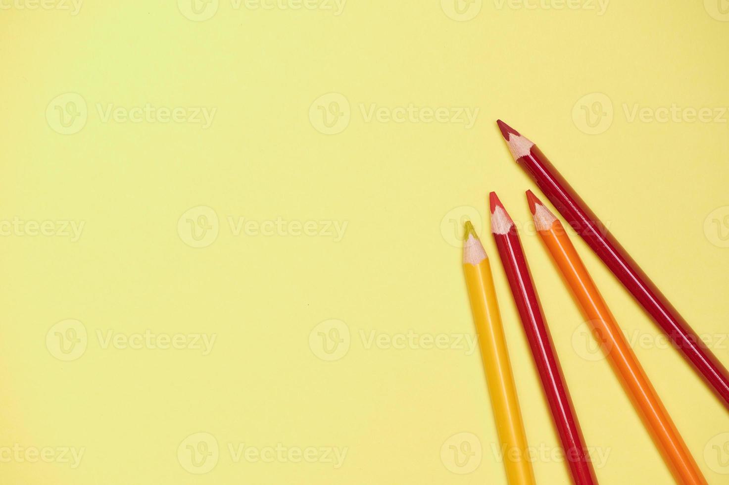 orange, red and yellow crayons on a bright yellow background photo