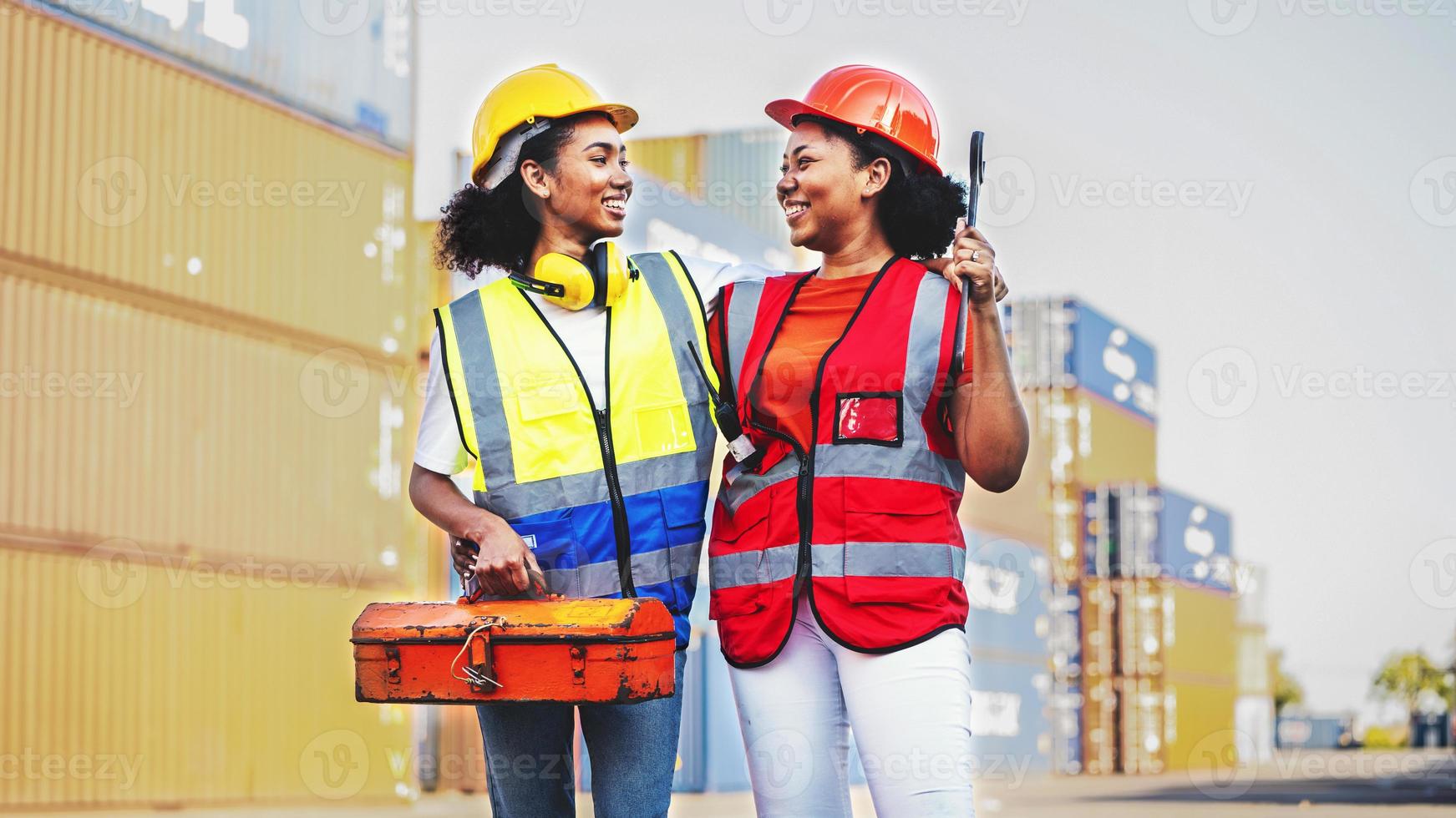 mujer técnica o trabajadora de mantenimiento sostiene una caja de herramientas mecánica cerca de un viejo contenedor de carga foto