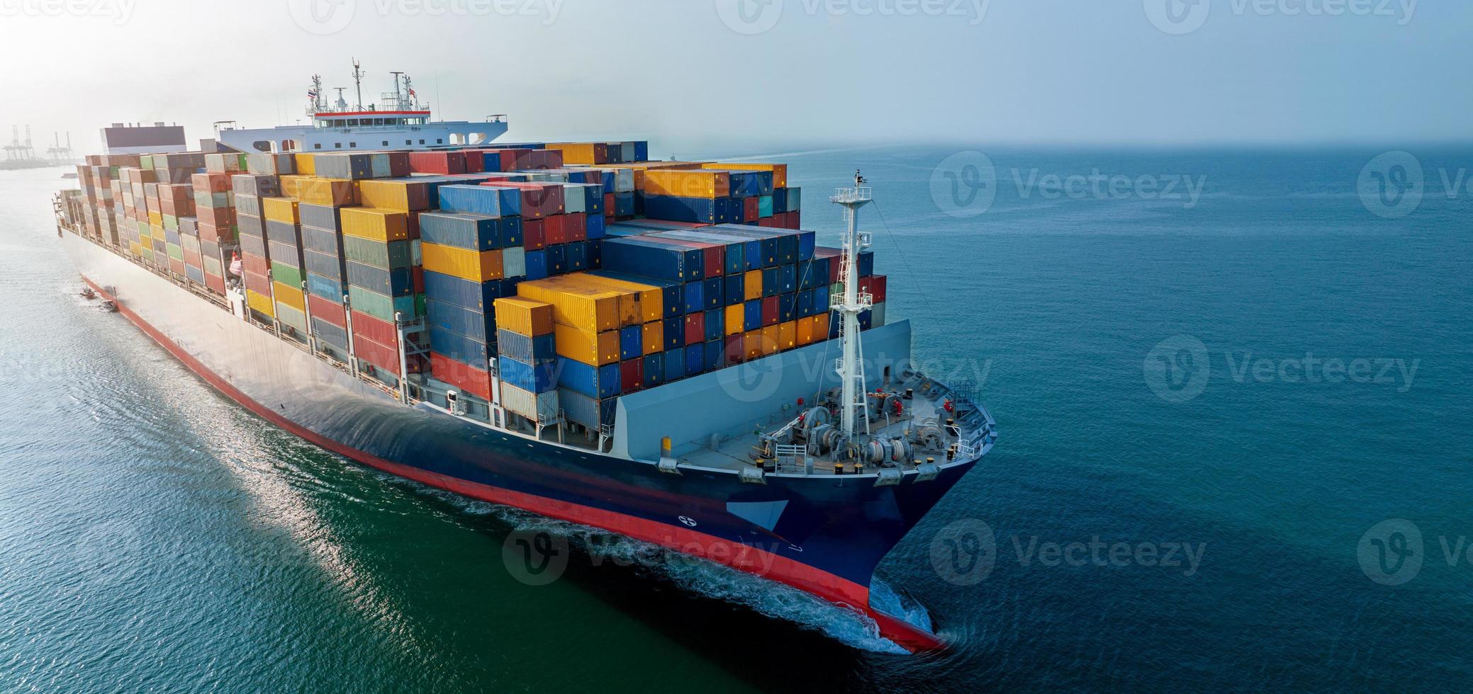 Aerial side view of cargo ship carrying container and running for