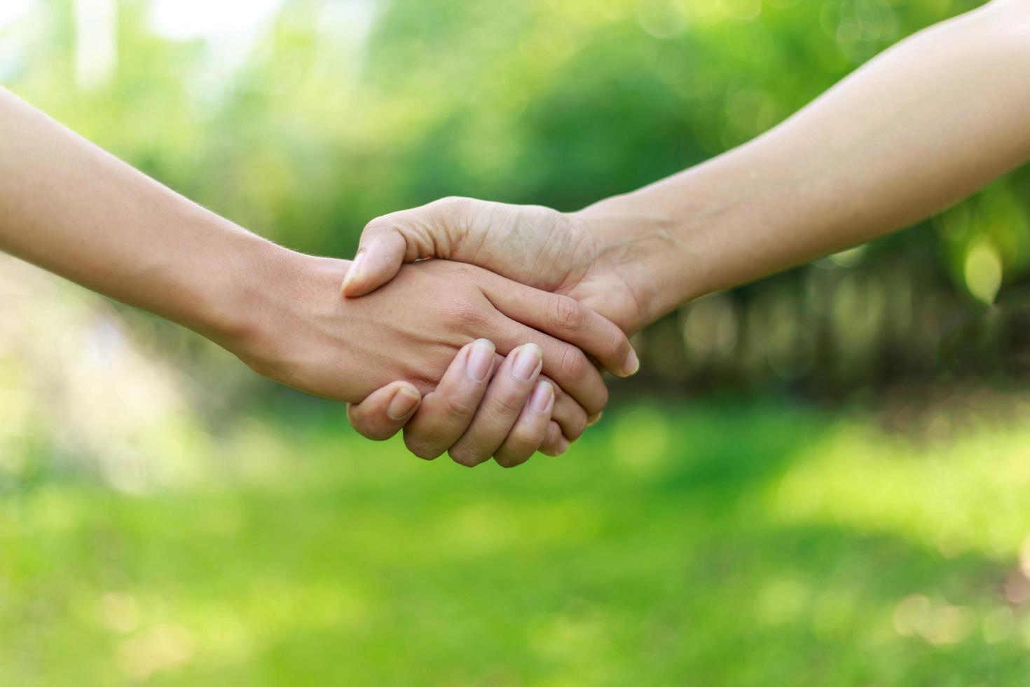 Two men shaking hands against nature background photo